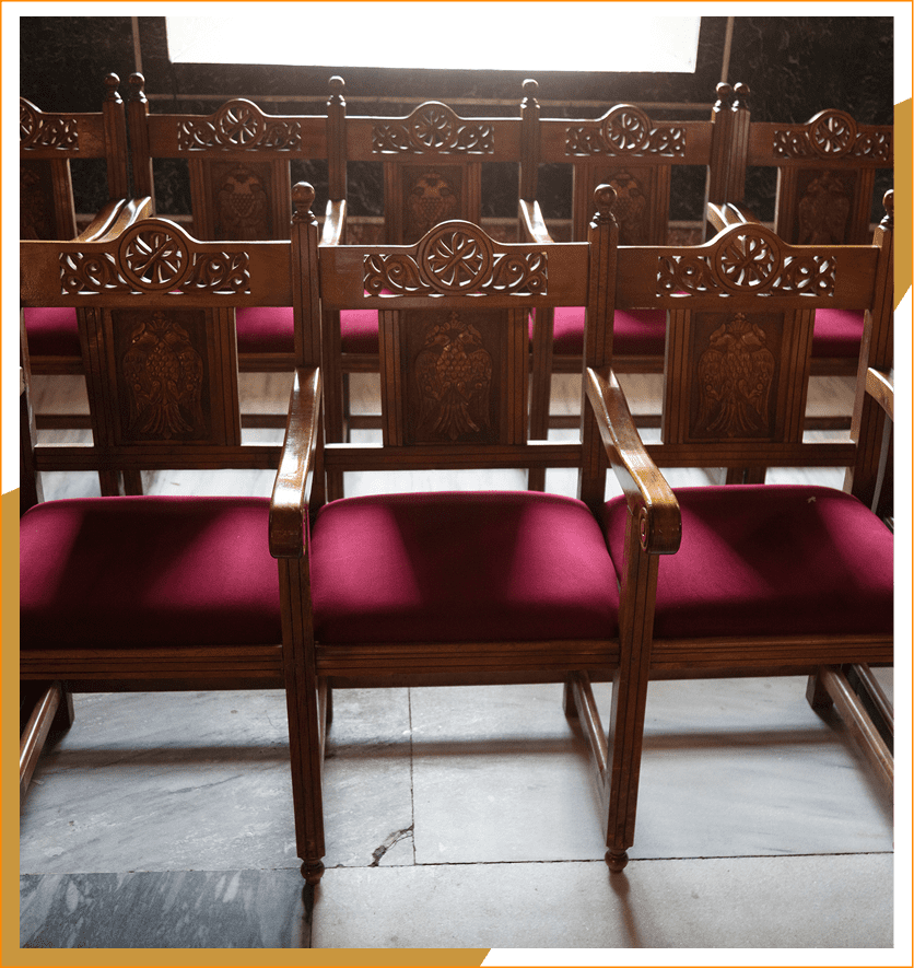 Wooden chairs with red cushions in rows.