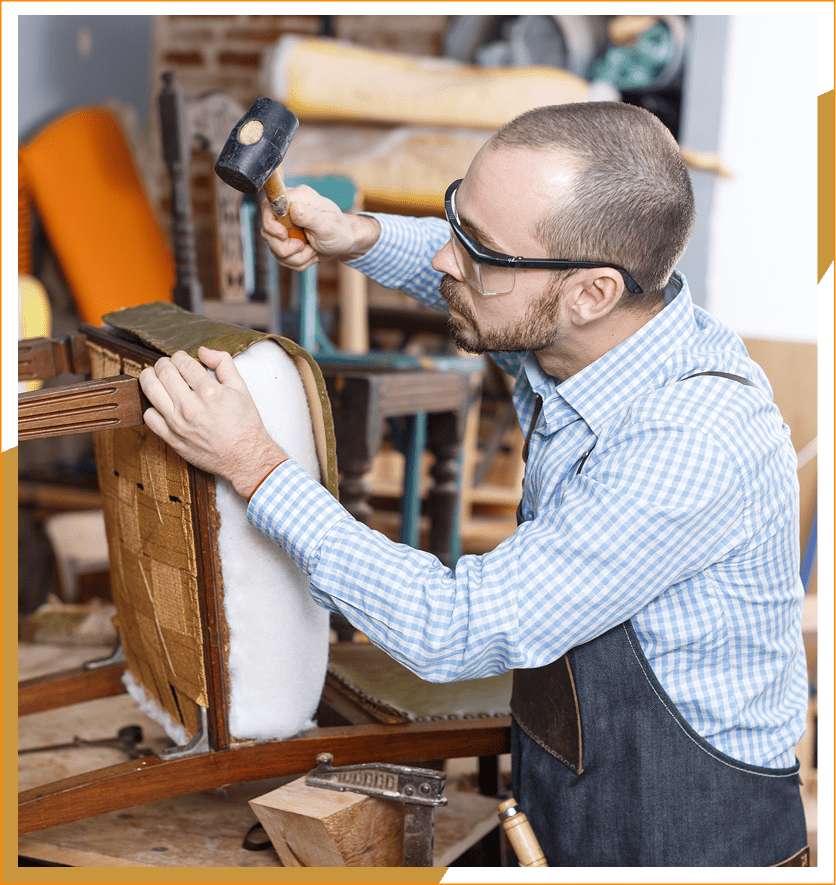 Man upholstering chair with hammer.